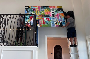 Experts hanging fine art from North Gallery in OKC for staging in a residence